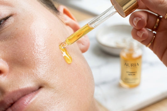A glass dropper applying golden vitamin C skin serum onto flawless radiant skin.
